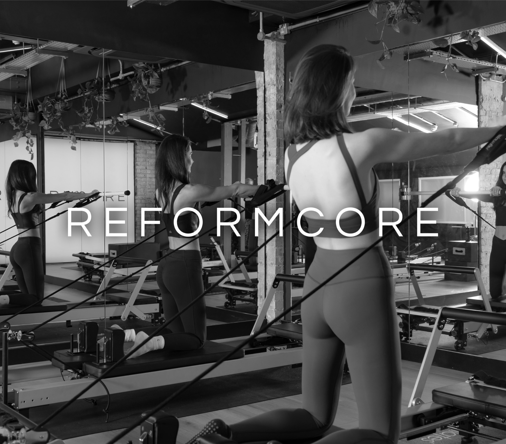 Clients in a Reformcore class performing resistance band arm work on the Reformer, focusing on posture, strength, and form in a luxury Pilates studio.